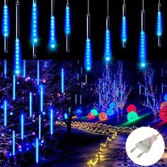 an image of christmas lights in the dark with blue and green lighting on trees, bushes and snow covered ground