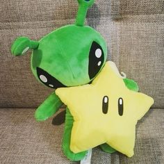 a green stuffed star sitting on top of a couch next to a plush toy frog