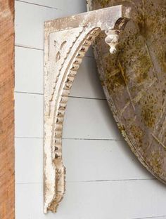 an old clock hanging on the side of a building next to a wooden wall with peeling paint