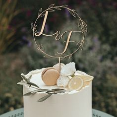 a white cake topped with a monogrammed topper sitting on a blue table