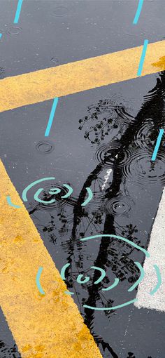 an umbrella is reflected in the puddles of water on the street floor with yellow and white lines