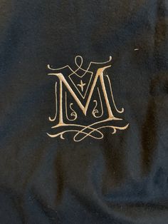 the monogrammed m logo is shown in gold on black fabric with an intricate design