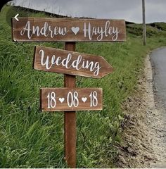 a wooden sign with the names of wedding and date on it in front of a grassy field