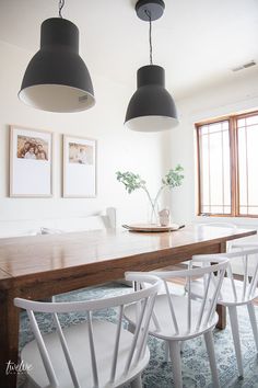 a dining room table with four chairs and two pictures on the wall above it,