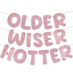 the words older wiser and hotter are spelled by pink glitter letters on a string