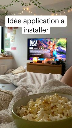 a person laying in bed with a bowl of popcorn and a tv on the wall