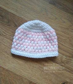 a pink and white knitted hat sitting on top of a wooden floor