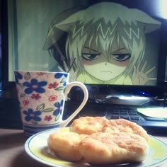 a plate with some food on it next to a cup and laptop computer, in front of an anime character