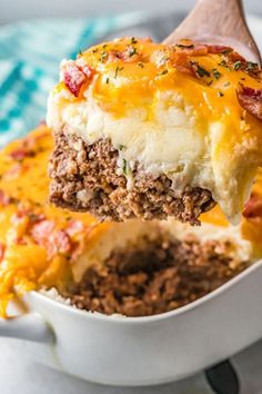 a piece of meat and cheese casserole being lifted from the casserole dish