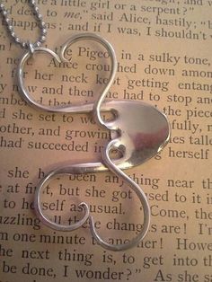 a silver heart shaped pendant sitting on top of an open book