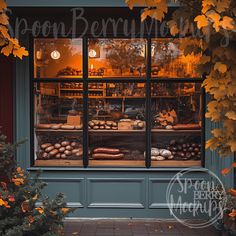 a store front with an assortment of baked goods in the window and autumn leaves around it