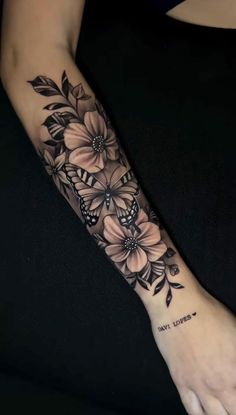 a woman's arm with flowers and butterflies tattooed on the left side of her arm