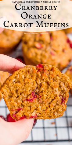 a hand holding an orange carrot muffin over a cooling rack