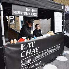 a man and woman standing behind a food cart