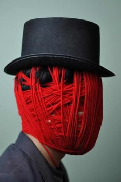 a man wearing a top hat with red thread on his face and hair in the shape of a human head