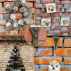 a brick wall with christmas decorations on it and a small white dog hanging from the front