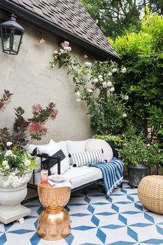 a white couch sitting on top of a blue and white checkered floor next to flowers