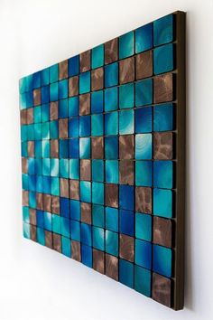 a blue and brown wall hanging on the side of a white wall with wood squares