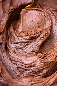 a close up of a spoon in a chocolate frosted cake