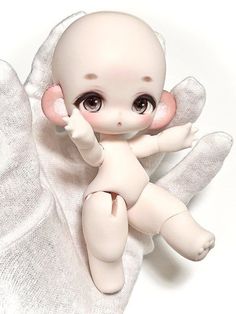 a small white doll sitting on top of a pillow