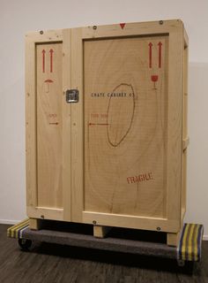 a wooden cabinet sitting on top of a hard wood floor next to a white wall