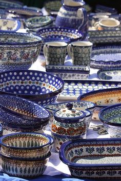 many bowls and plates on a table with blue cloth under the bowl are sitting in rows