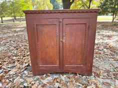 an old wooden cabinet sitting on top of leaves