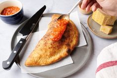 a person is eating some food on a plate with a knife and fork next to it