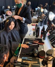 a woman getting her hair cut at a salon while another woman watches from the side