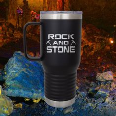 the rock and stone travel mug is shown in front of some rocks with lights on them