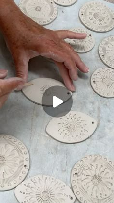 a person is working on some white ceramic plates with their hands and fingers pointing at them