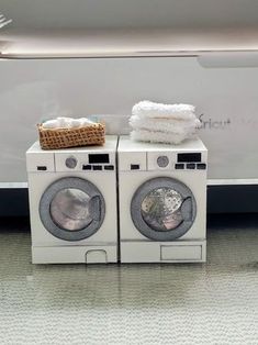 two washers stacked on top of each other in front of a dryer and towel dispenser