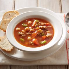 a white bowl filled with soup next to two slices of bread on top of a table