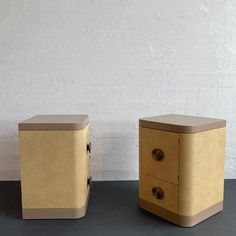 two side tables sitting next to each other in front of a white wall