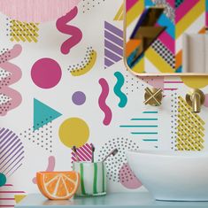 a bathroom with colorful wallpaper and a bowl of fruit on the counter next to it