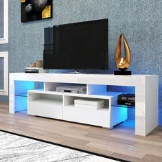 a white entertainment center with blue lights on the side and a flat screen tv mounted to it's wall