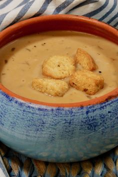 a bowl filled with soup and crackers sitting on top of a blue and white table cloth