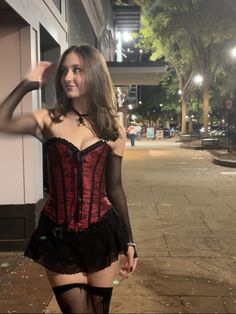 a woman in a corset is posing for the camera on a city street