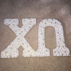 the letters xo and o are made out of plastic beads on the floor in front of a carpeted area