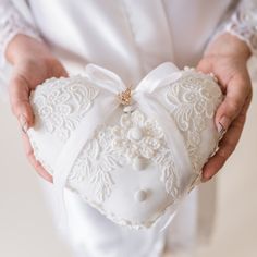 a person holding a white heart shaped box with a bow on it's side