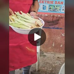 a person in an apron holding a bowl full of oklerd beans on the street