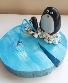 two penguins are sitting on top of a piece of driftwood that has been painted blue and white