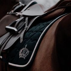 the back end of a brown horse's saddle with black and white stitching