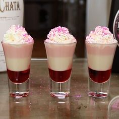 three glasses filled with liquid and topped with whipped cream, sprinkled with pink flowers