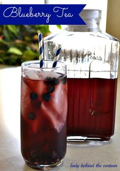 blueberry tea in a glass with ice and strawberries next to it on a table