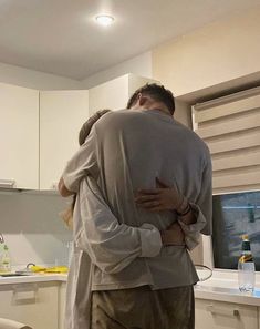 two people hugging each other in the kitchen