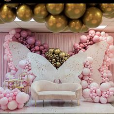 a room filled with balloons and furniture in front of a pink curtained wall that has a large butterfly on it