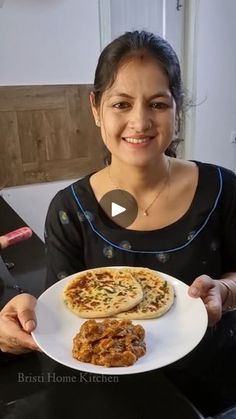 a woman holding a plate with two pizzas on it