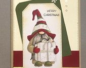 a christmas card with an image of a gnome holding a gift box and the words merry christmas written on it