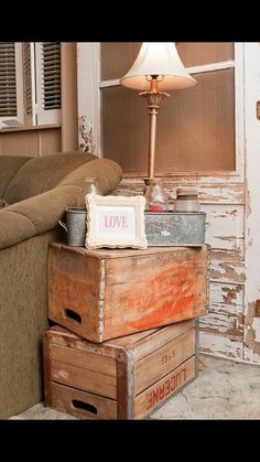 two wooden boxes stacked on top of each other in front of a couch with a lamp